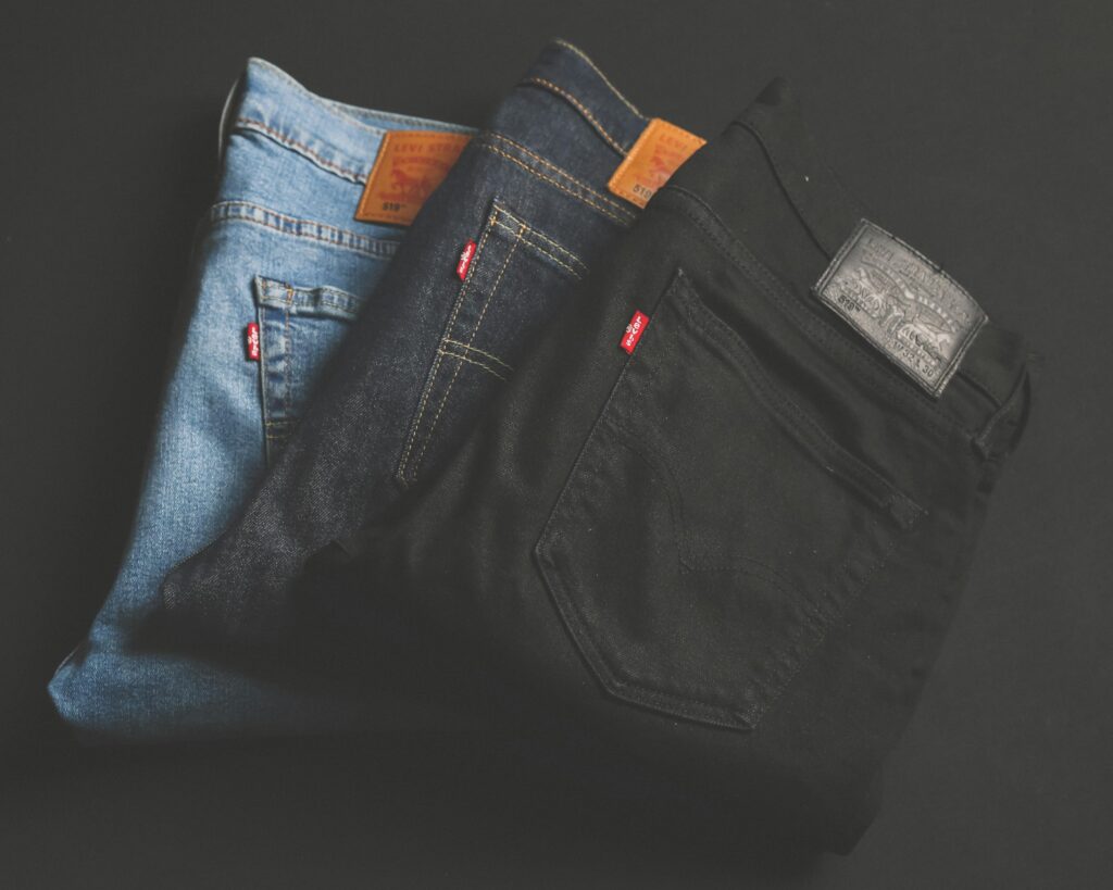 A stack of blue, dark, and black denim jeans folded on a dark surface.